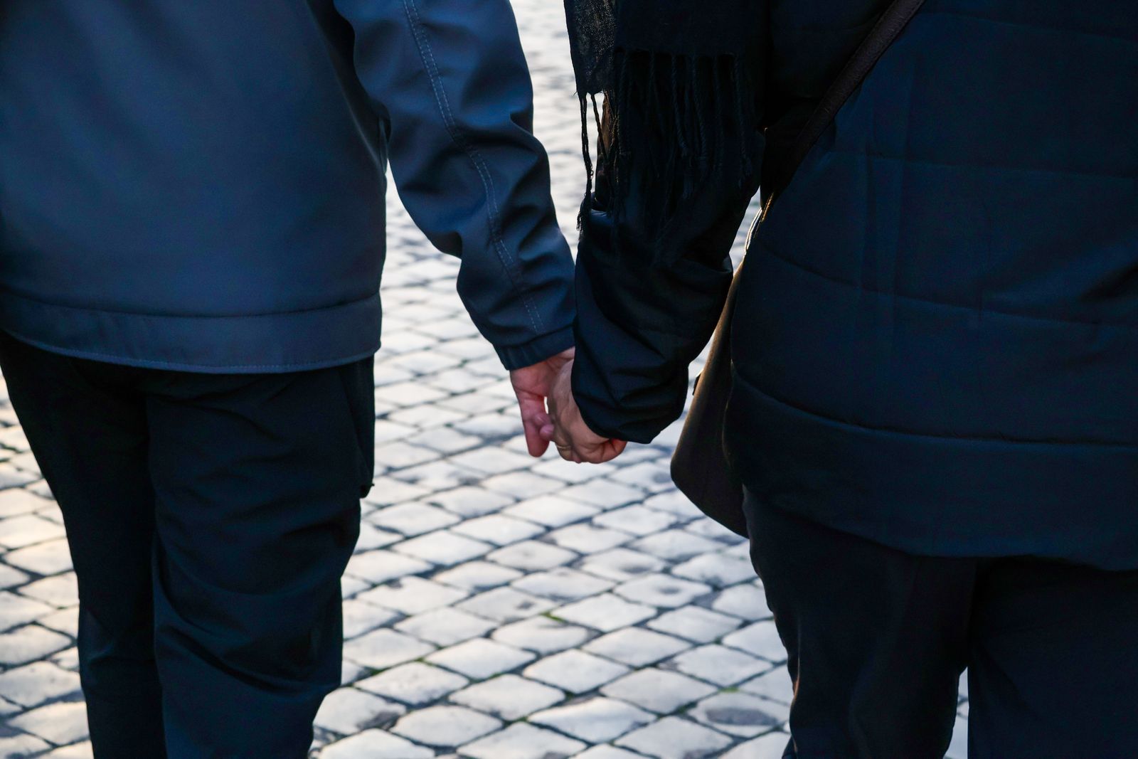 Two people holding hands walking together outdoors