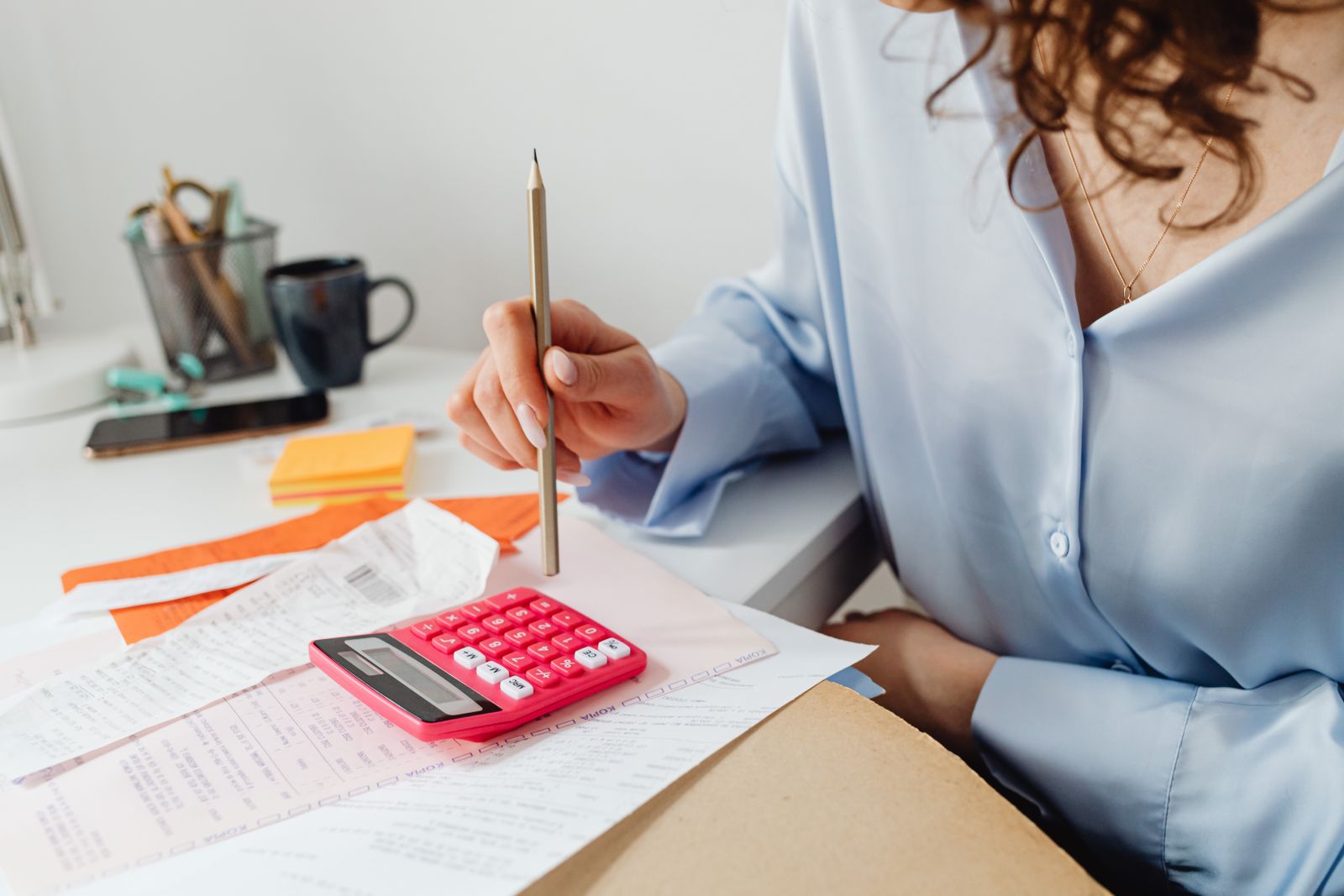 Person using a calculator while reviewing bills at a desk