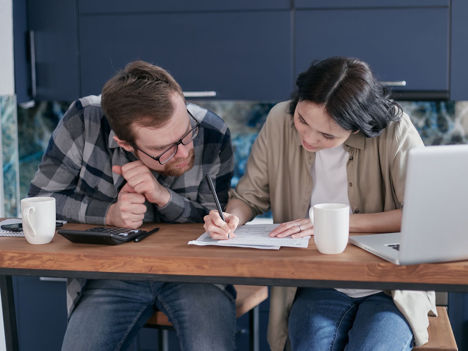 Couple reviewing bills and paperwork together at their kitchen table