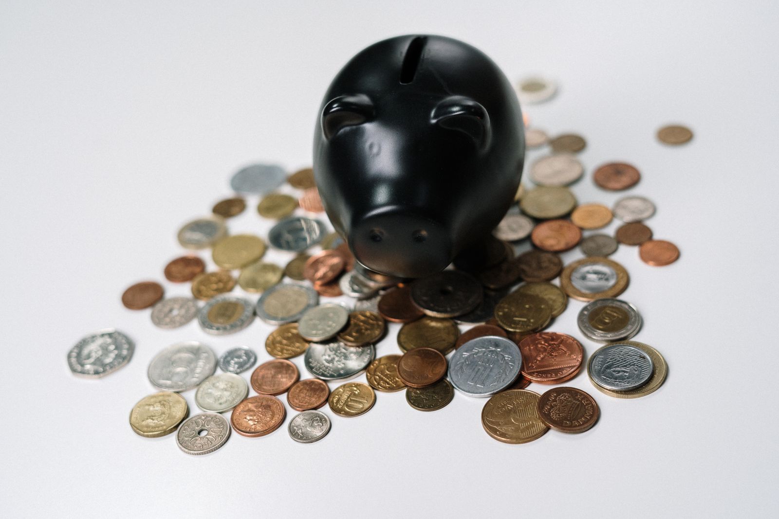 Black piggy bank surrounded by scattered coins
