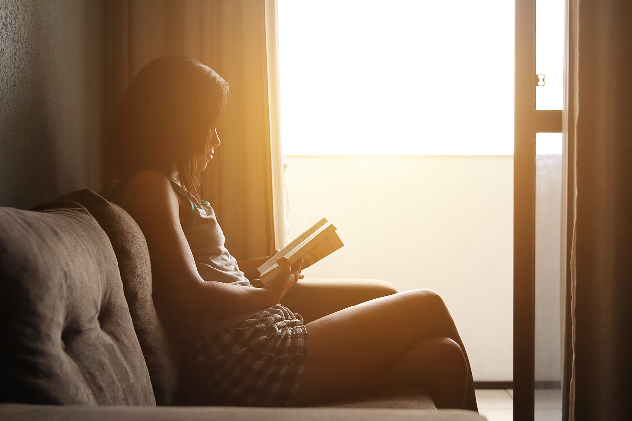 A woman relaxing at home on the couch while reading and thinking