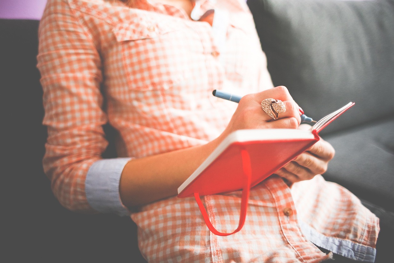 A woman sitting comfortably at home reviewing her notes with a cup of coffee