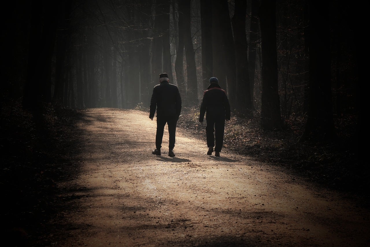 A middle-aged couple walking together outdoors on a sunny autumn day