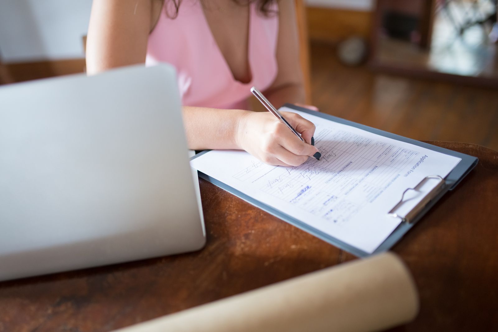 Woman signing a private PPO application form next to her laptop at home
