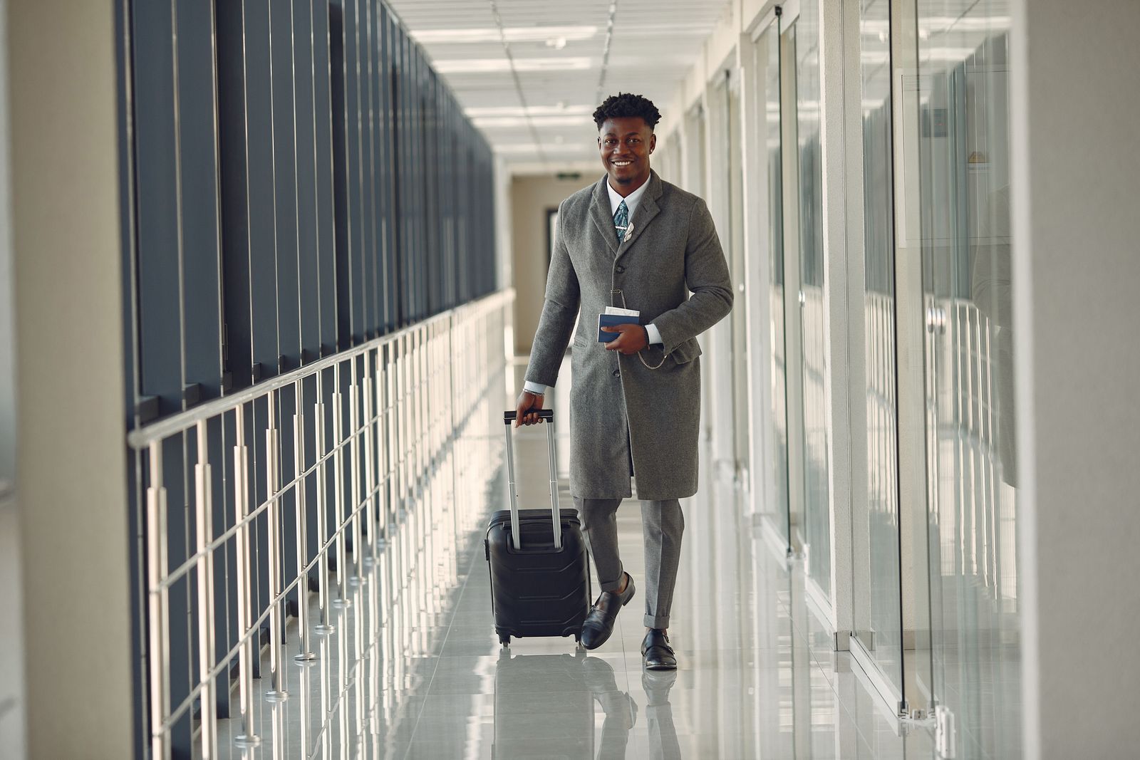 Traveler with a suitcase and passport walking through an airport corridor